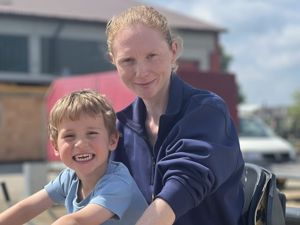 Lächelnde Frau und Kind draußen an einem sonnigen Tag.