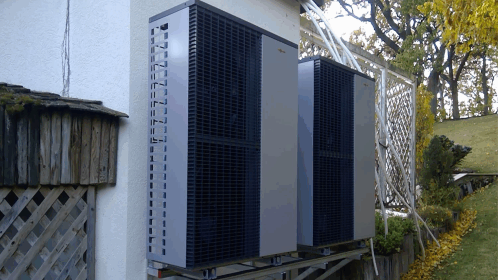 Zwei Wärmepumpen neben einem Haus im Herbst.