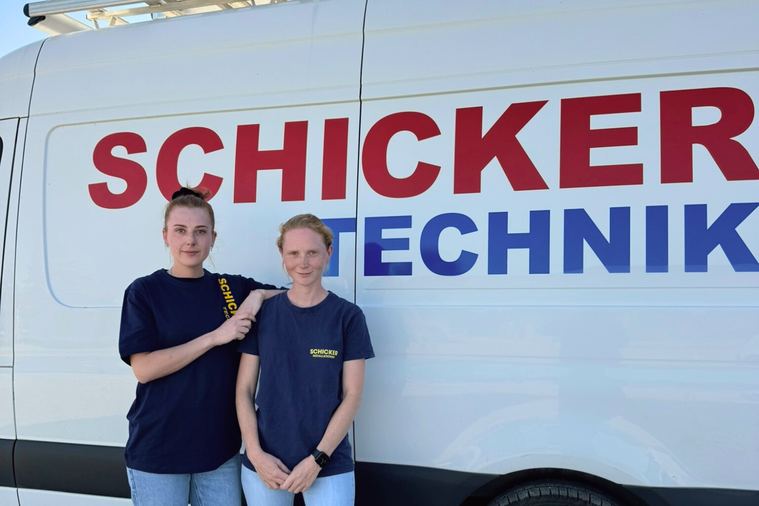 Zwei Mitarbeiterinnen vor einem Firmenauto von Schicker Technik.